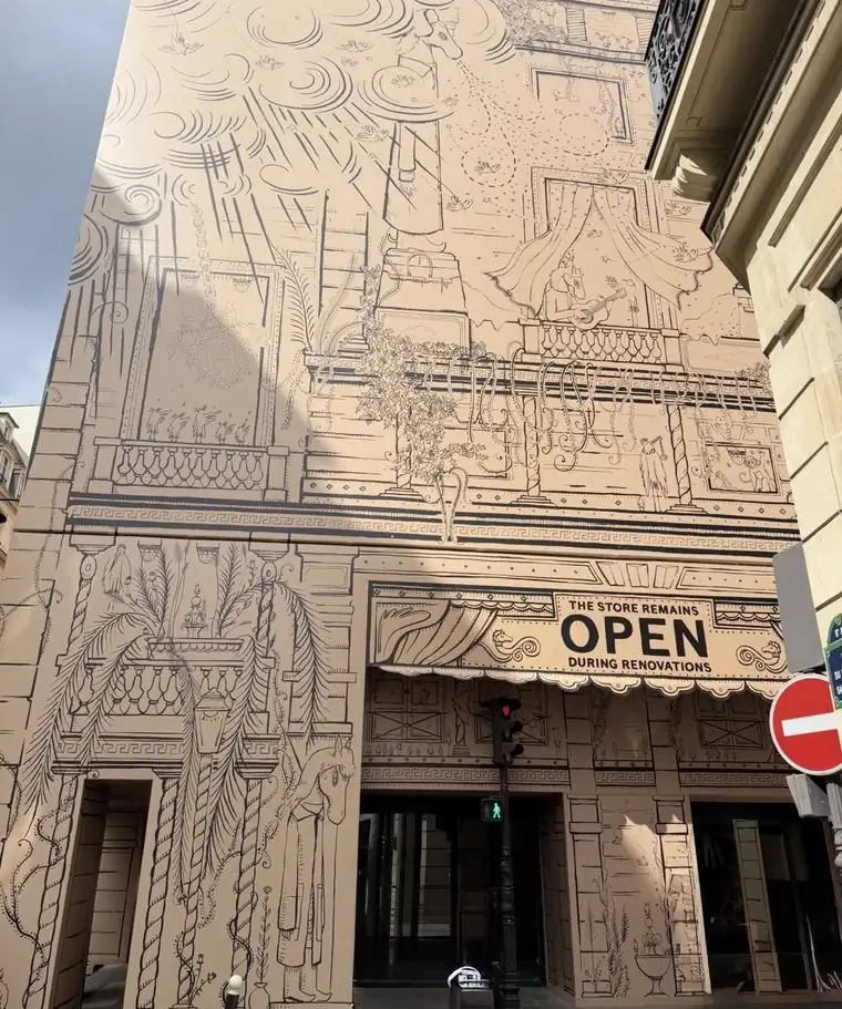 The Hermès Faubourg Saint-Honoré façade under renovation, hidden behind decorative panels, the entrance open beside them