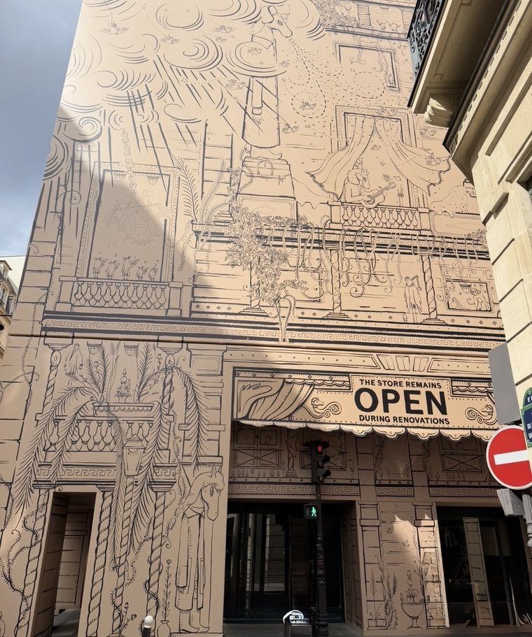 The Hermès Faubourg Saint-Honoré façade under renovation, hidden behind decorative panels, the entrance open beside them